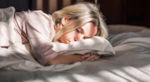Frau liegt nachts wach im Bett als Symbol für Schlafprobleme bei Angst