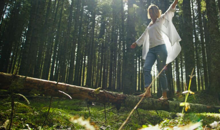 Frau geht selbstbewusst durch einen hellen Wald als Symbol für Ängste überwinden