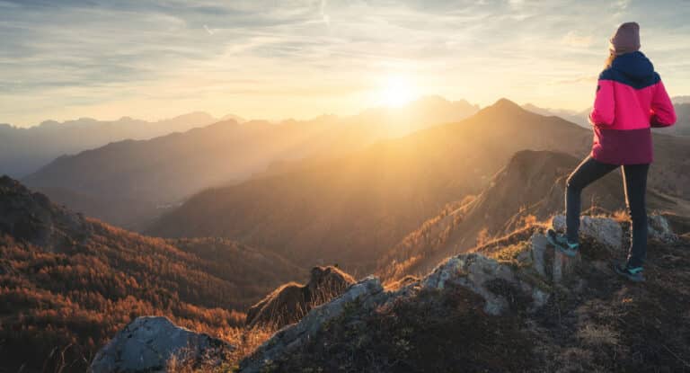 Frau steht kraftvoll auf einem Hügel als Symbol für Angst überwinden