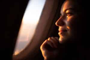 Frau blickt aus dem Flugzeugfenster als Symbol für Angst vorm Fliegen