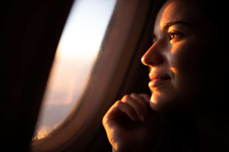 Frau blickt aus dem Flugzeugfenster als Symbol für Angst vorm Fliegen