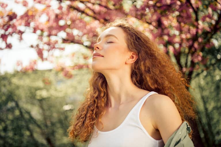 Frau steht ruhig in der Natur und atmet bewusst zur Beruhigung bei Angst und Panik