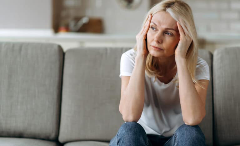 Erschöpfte Frau am Schreibtisch als Symbol für Burnout